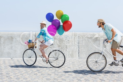 Couple cycling with balloons in sunshine