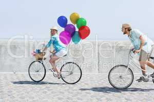 Couple cycling with balloons in sunshine