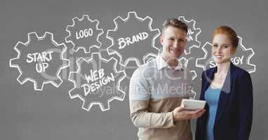 Happy business people holding a tablet against grey background with graphics