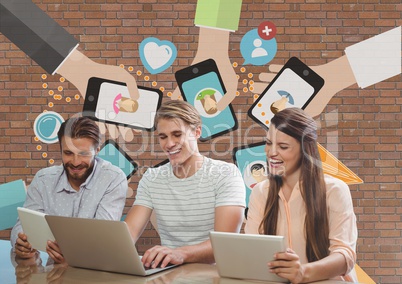 Happy business people at a desk looking at a computer and a tablet against brick wall with graphics