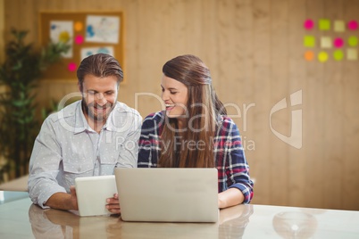 Happy business people at a desk looking at a tablet
