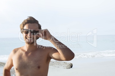 Happy man at the beach holding sunglasses