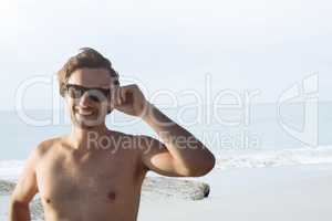Happy man at the beach holding sunglasses