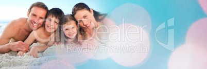 Family lying on beach smiling at camera wide shot