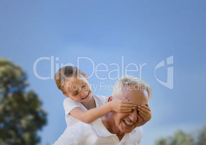 Girl and grandfather piggyback against sky and blurry trees