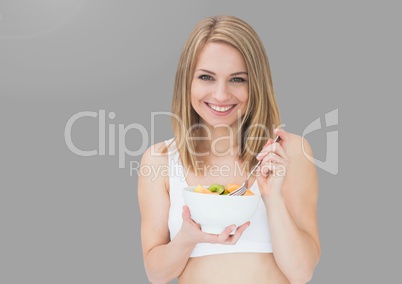 Portrait of woman eating salad with grey background