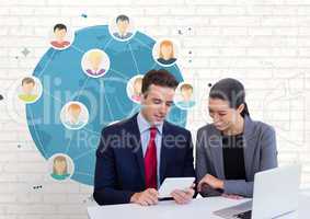 Happy business people at a desk looking at a tablet against white wall with graphics