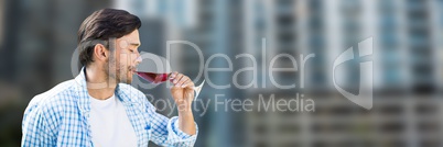 Man tasting wine against blurry buildings