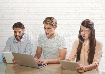 Business people at a desk looking at a tablet and a computer