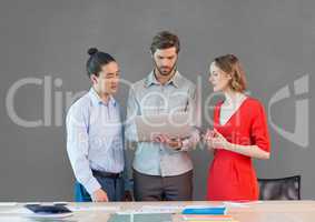 Business people at a desk looking at a tablet against grey background