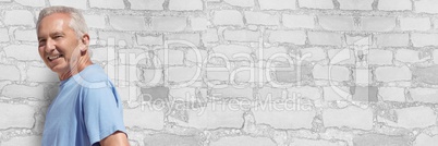 Elderly man against white brick wall