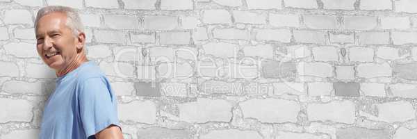 Elderly man against white brick wall