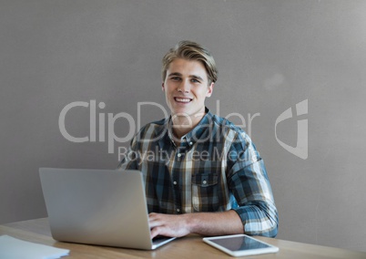 Happy business man at a desk using a computer against grey background