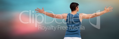 Back of man in training gear with arms out against blurry blue background
