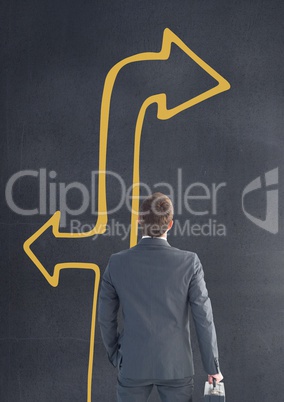 Business man looking up against grey background with yellow arrow
