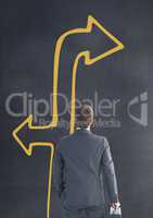 Business man looking up against grey background with yellow arrow