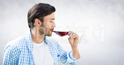 Man tasting wine against white wall