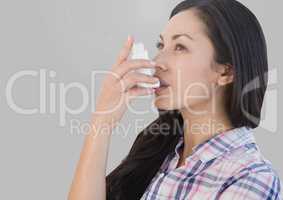 Portrait of woman using asthma inhaler with grey background