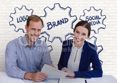 Happy business people at a desk holding a paper against white wall with graphics