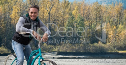 Middle aged man on bicycle against forest
