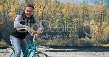 Middle aged man on bicycle against forest