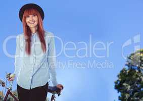 Millennial woman with bicycle against sky and tops of trees