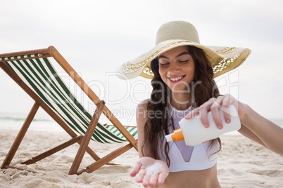 Happy woman at the beach putting on cream