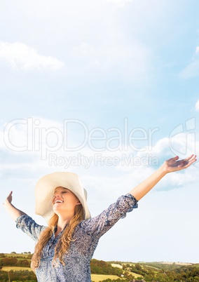 Millennial woman with arms out against hills and Summer sky
