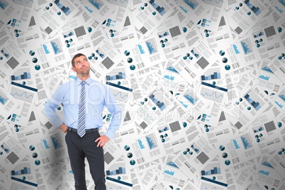 Confident businessman standing thinking with business newspapers in background