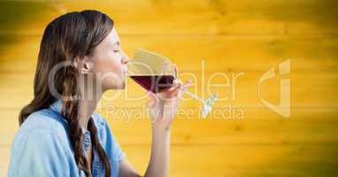 Woman tasting wine against blurry yellow wood panel