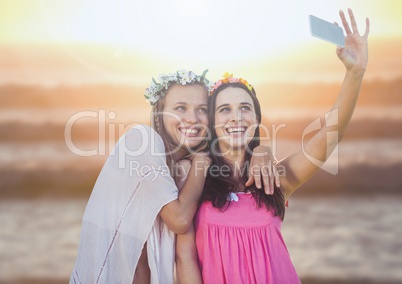 Women taking casual selfie photo in front of sea sunset