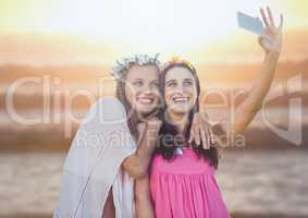 Women taking casual selfie photo in front of sea sunset
