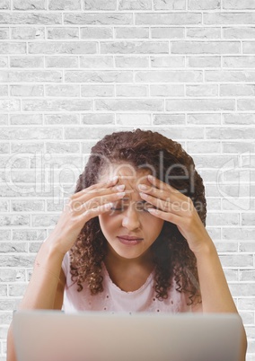 Frustrated business woman at a desk using a computer against white wall