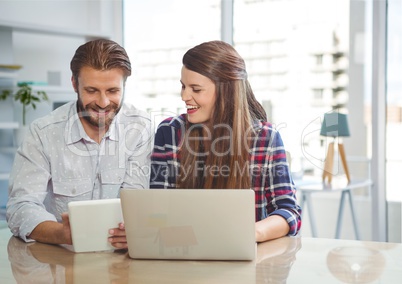Happy business people at a desk looking at a tablet