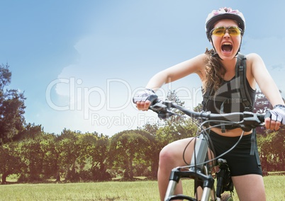Woman screaming on bicycle against field