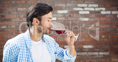 Man tasting wine against red brick wall