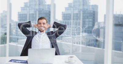 Happy business man at a desk sitting against city background