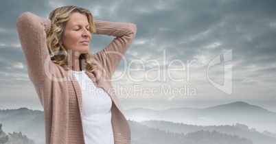 Woman holding hands on head practicing casual mindfulness in front of mountain landscape