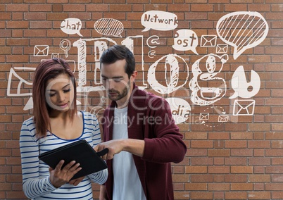 Business people looking at a tabler against brick wall with graphics