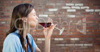 Woman tasting wine against red brick wall
