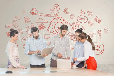 Business people at a desk looking at computers and tablets against white wall with red graphics