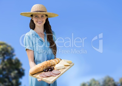 Woman with food platter against sky and blurry trees