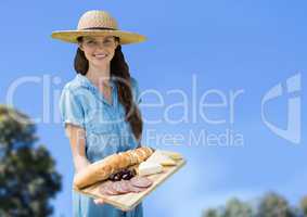 Woman with food platter against sky and blurry trees
