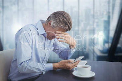 Business man at a desk looking at a phone