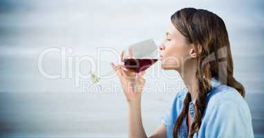 Woman tasting wine against blurry blue wood panel