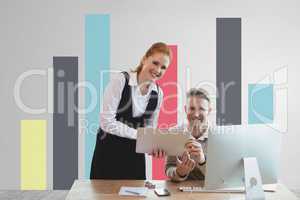 Happy business people at a desk using a tablet against white wall with graphics