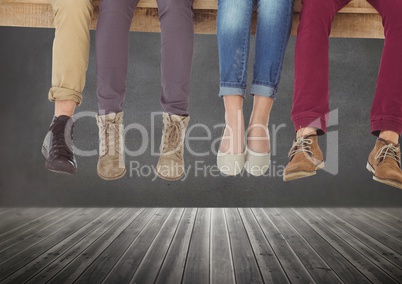 Group of people's legs sitting on wood in front of grey background