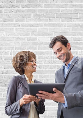 Happy business people using a tablet against white wall