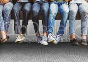 Group of people's legs sitting on bench in front of grey background