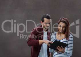 Happy business people using a tablet against brown background